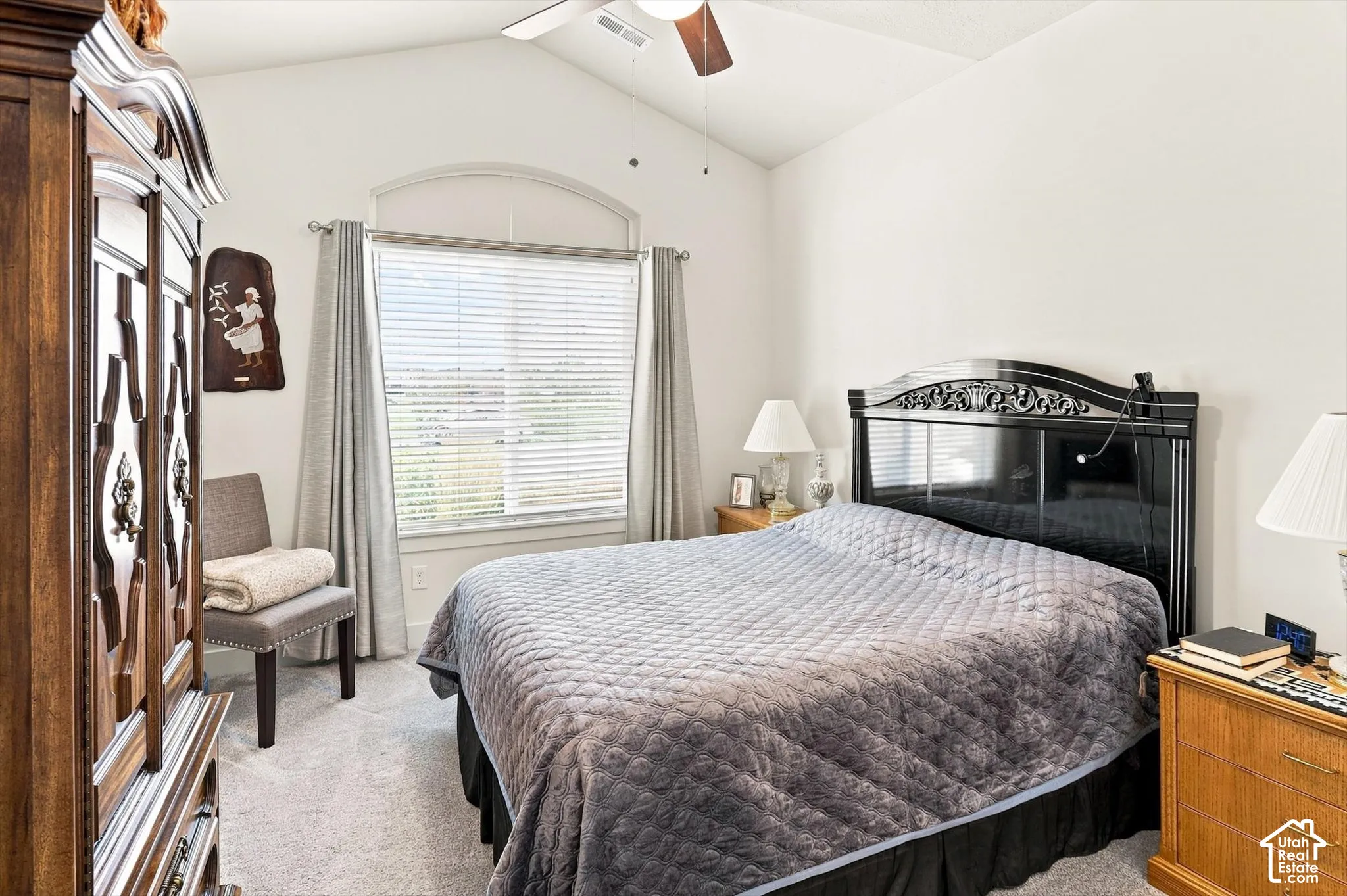 Vaulted ceiling with ceiling fan, arched window with blinds, and light-tone carpeting