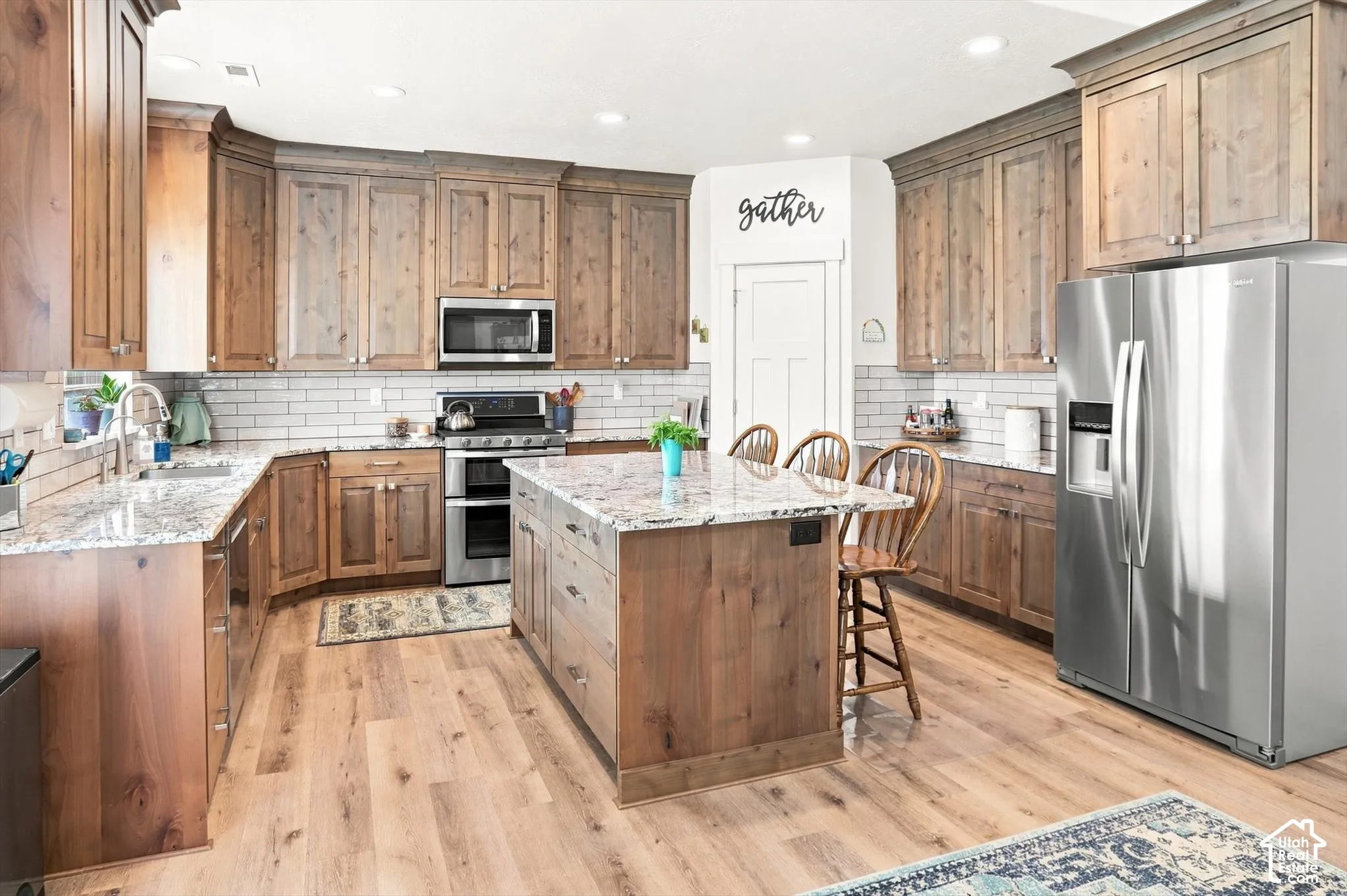 Kitchen featuring wood-finish flooring, a central island with countertop, extensive wood cabinetry, and stainless steel appliances