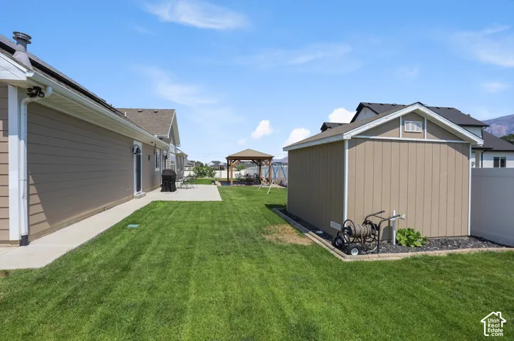 Expansive lawn area featuring a concrete patio, a detached storage shed, and a privacy fence