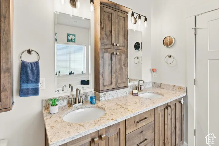 Dual vanity with light-toned countertop, wood-finish cabinetry, and individual mirrors