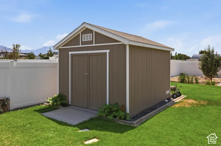 Outdoor storage shed with double doors, wood-look siding, and a gabled roof