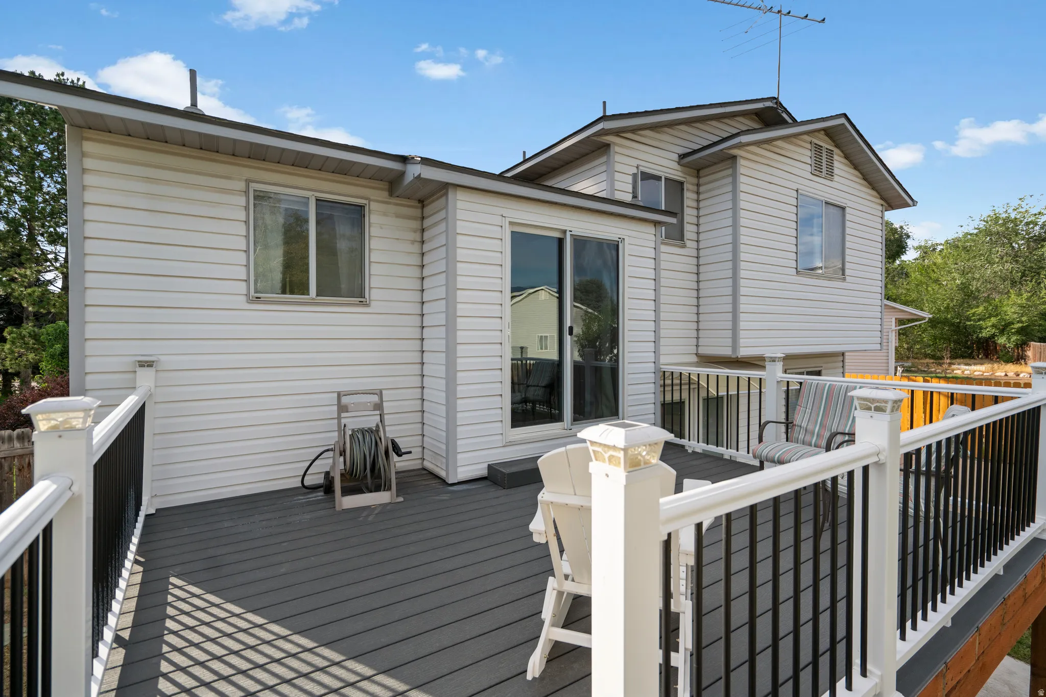 Elevated deck with composite decking, white railing with black balusters, and solar post caps