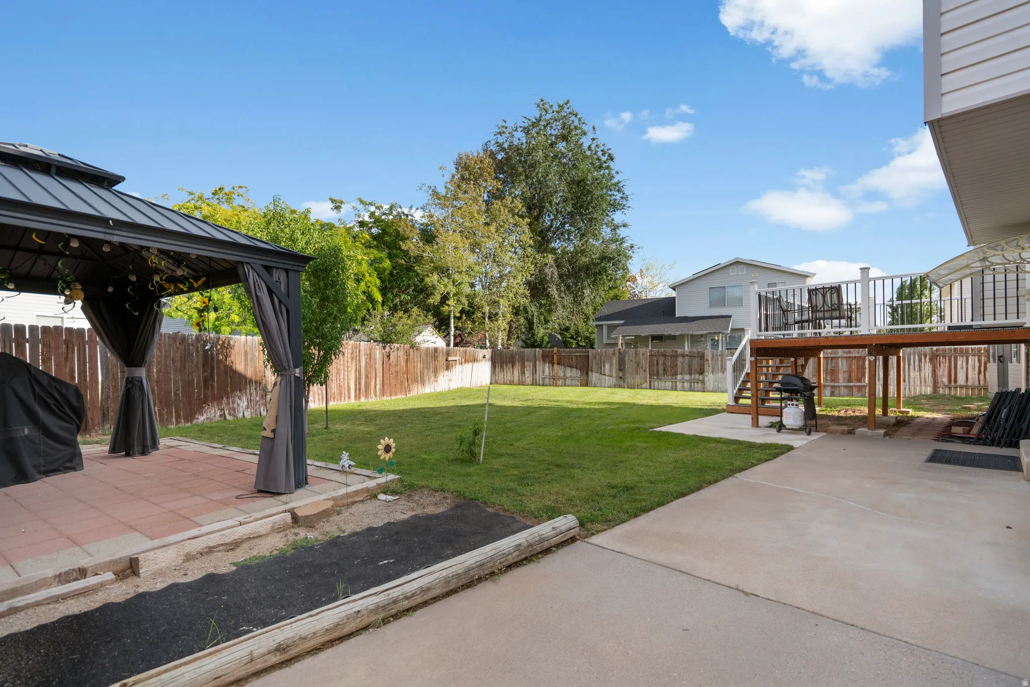 Expansive backyard featuring a lush lawn, privacy fencing, and a concrete patio