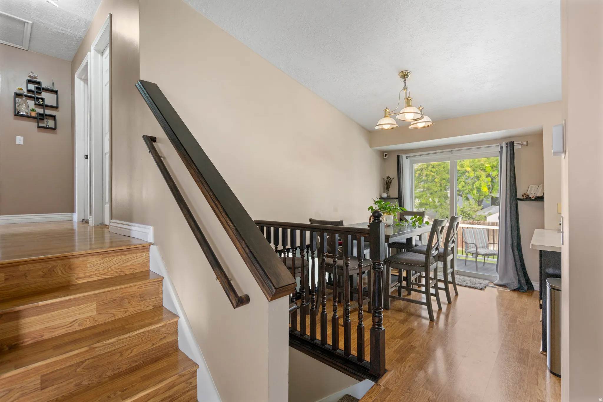 Hardwood stairs and flooring, dark wood railing, sliding glass door to exterior, built-in breakfast bar, and ceiling-mounted light fixture