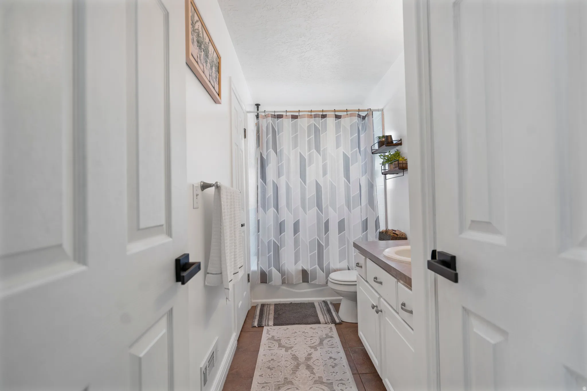White paneled doors with black hardware, tile flooring, and a white vanity with an integrated sink
