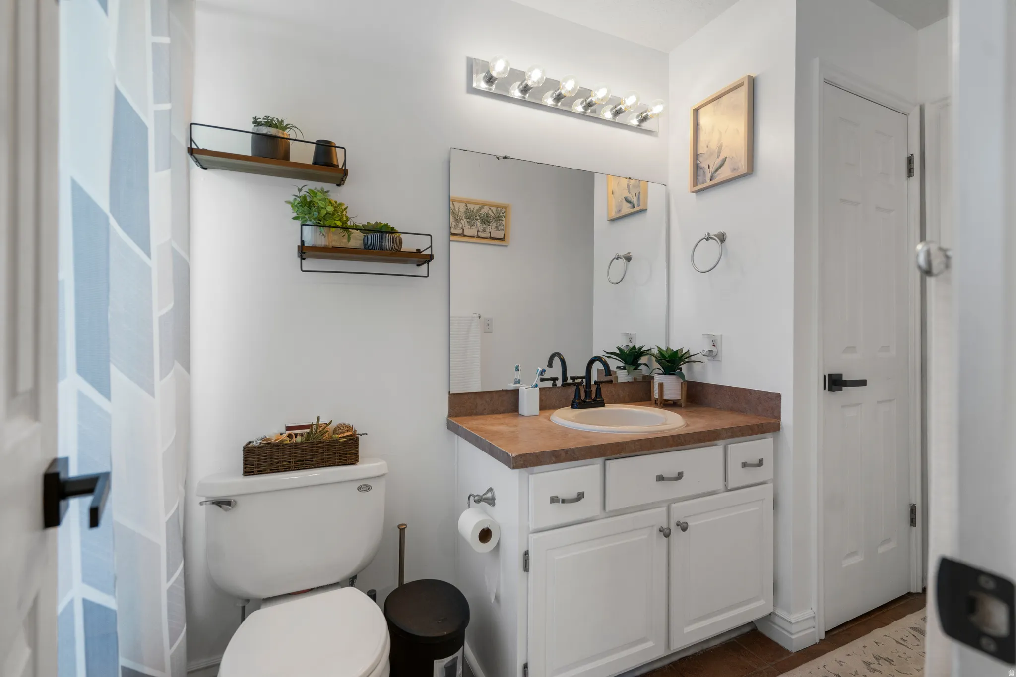 Vanity with an integrated sink and matte black faucet, wall-mounted mirror, and white cabinetry