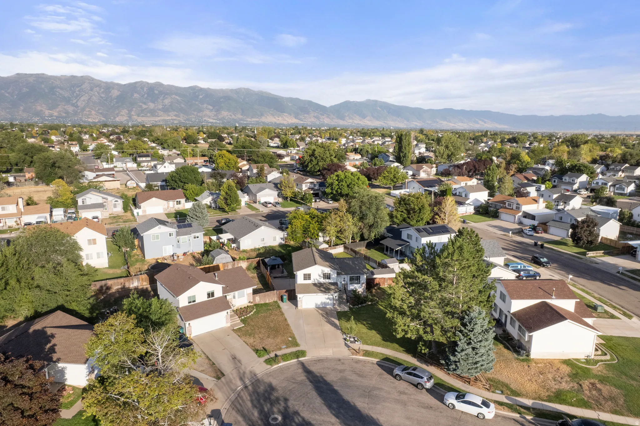 Residential neighborhood with established trees and mountain backdrop