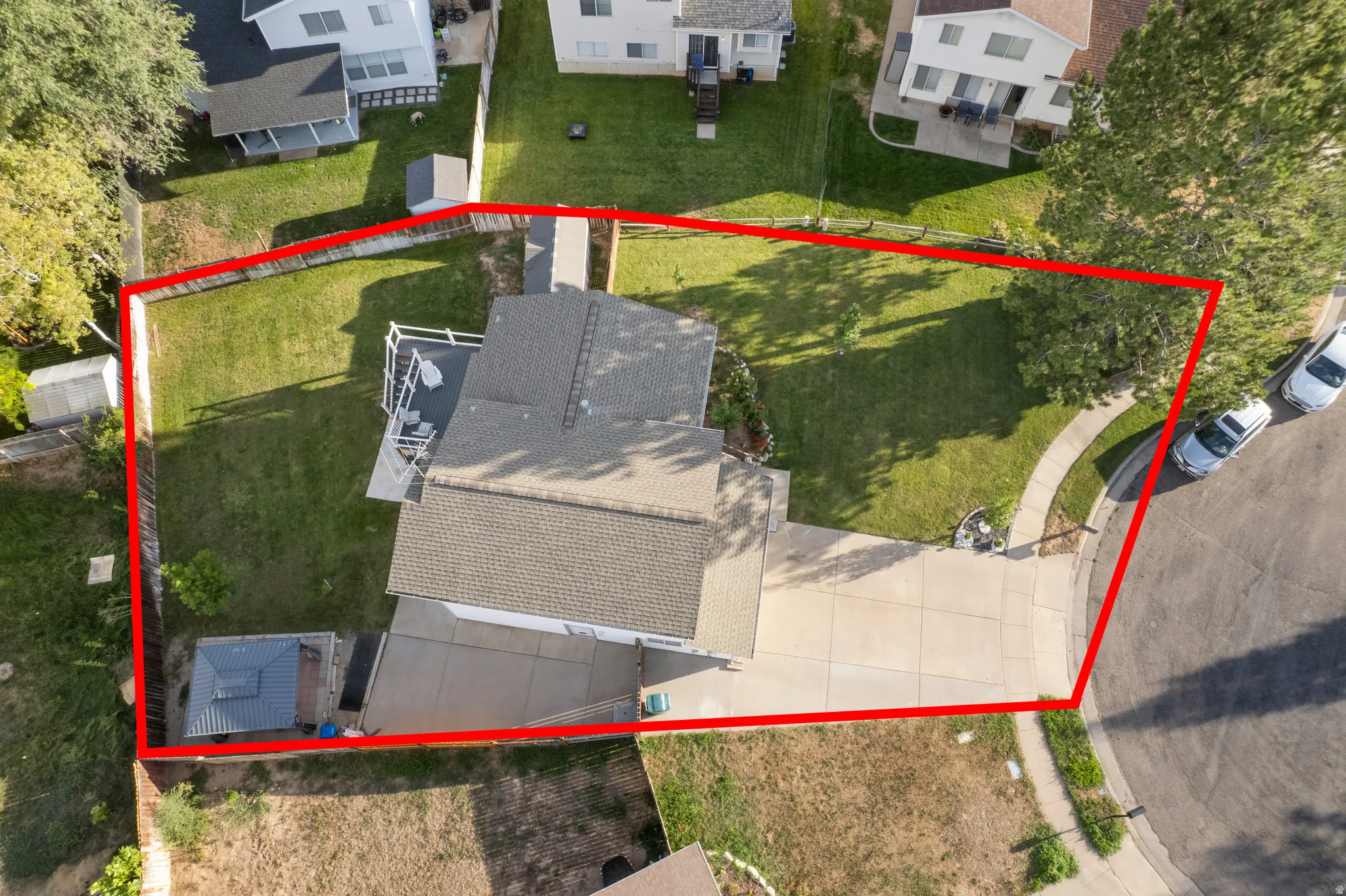 Expansive lawn areas, a paved driveway, and established trees define the property