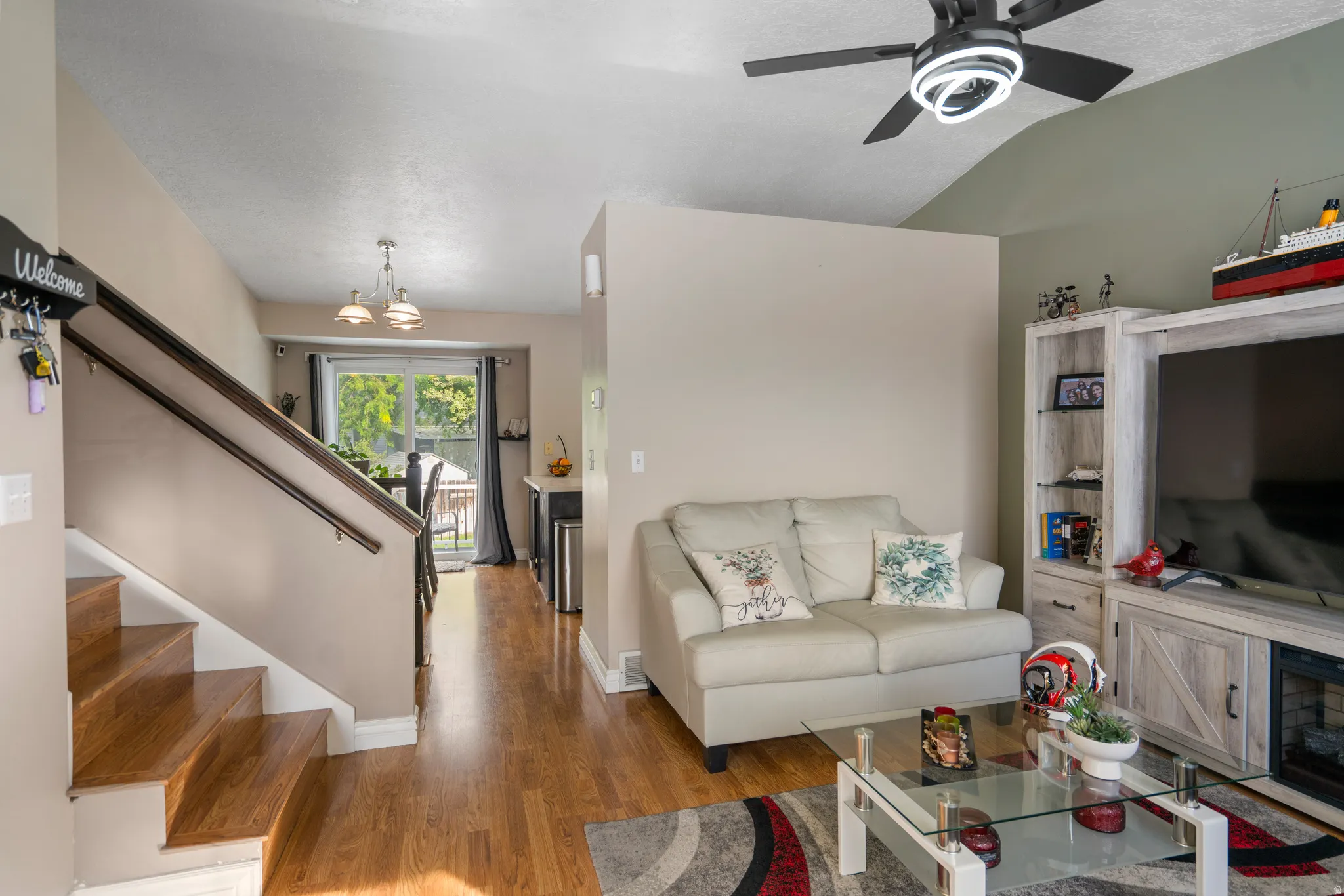 Wood-finish flooring throughout, vaulted ceiling, built-in shelving, and a modern ceiling fan with integrated lighting