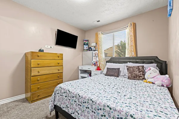 Recessed window with blinds, mounted television, and carpeted flooring