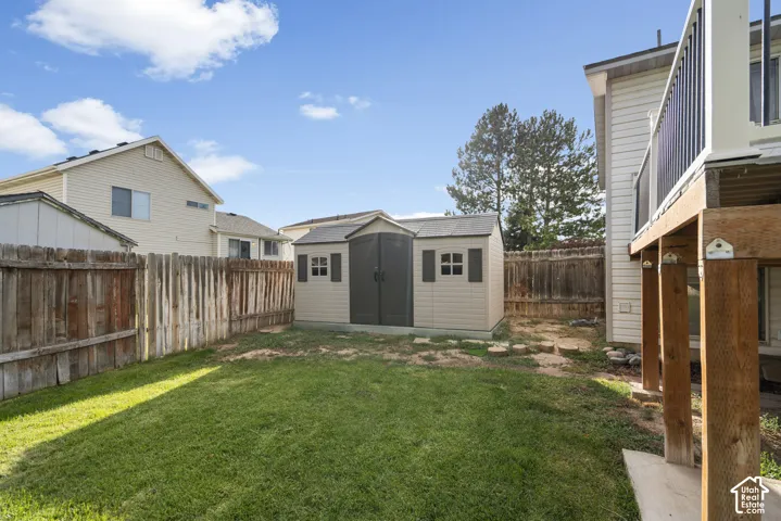 Fenced backyard featuring a manicured lawn, a detached storage shed, and an elevated wood deck