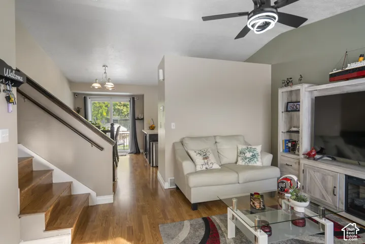 Wood-finish flooring throughout, vaulted ceiling, built-in shelving, and a modern ceiling fan with integrated lighting