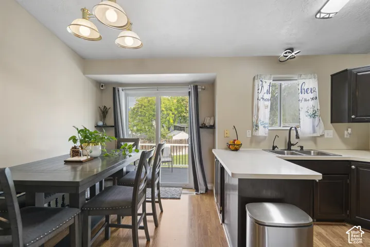 Wood-finish flooring, dark wood cabinetry, light countertops, kitchen sink with matte black faucet, and a sliding glass door to an outdoor deck
