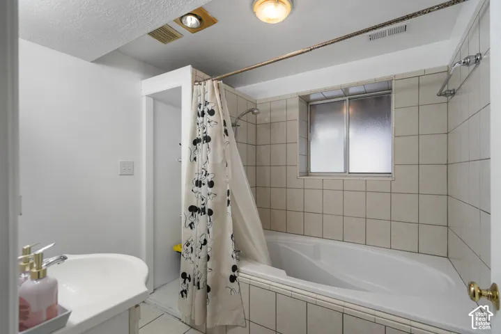 White ceramic tile shower surround with a built-in tub, textured glass window, and a wall-mounted light fixture