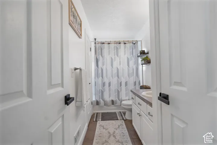 White paneled doors with black hardware, tile flooring, and a white vanity with an integrated sink