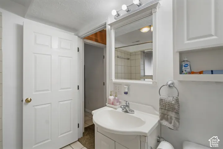 White paneled door, white vanity with integrated sink, wall-mounted mirror, and overhead strip lighting