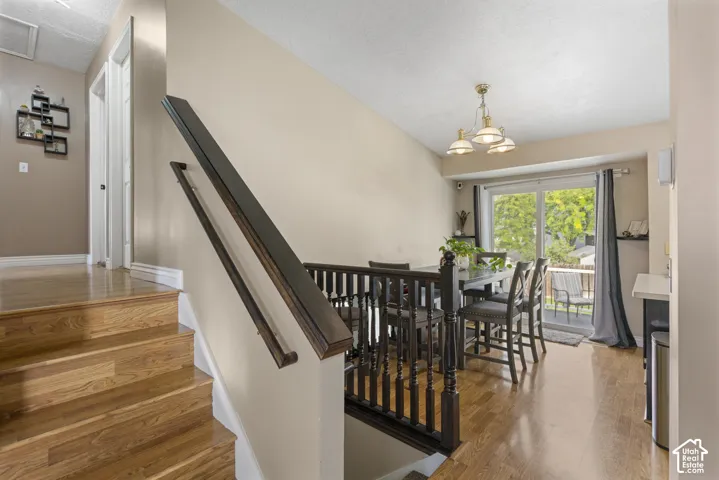 Hardwood stairs and flooring, dark wood railing, sliding glass door to exterior, built-in breakfast bar, and ceiling-mounted light fixture