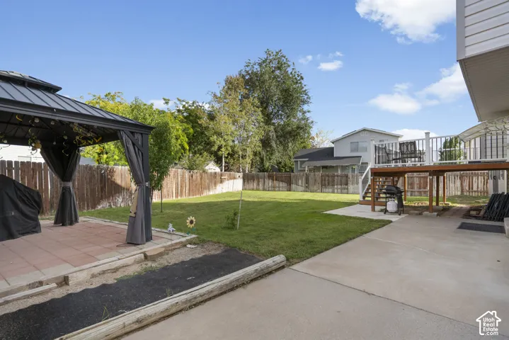 Expansive backyard featuring a lush lawn, privacy fencing, and a concrete patio