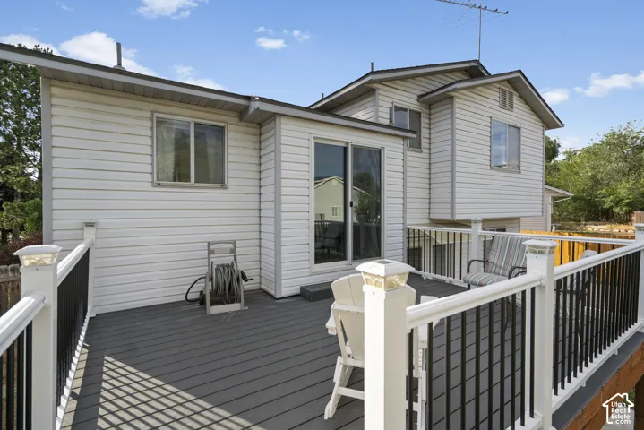 Elevated deck with composite decking, white railing with black balusters, and solar post caps