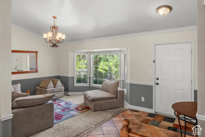 Vaulted ceiling with an ornate chandelier, bay window, two-tone wall treatment, and tile flooring