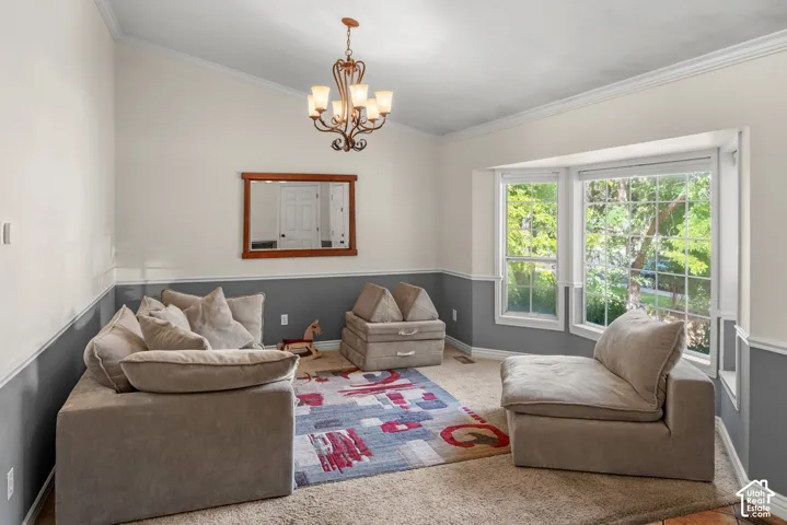Vaulted ceiling with an ornate chandelier, two-tone wall paneling, a large bay window, and carpeted flooring