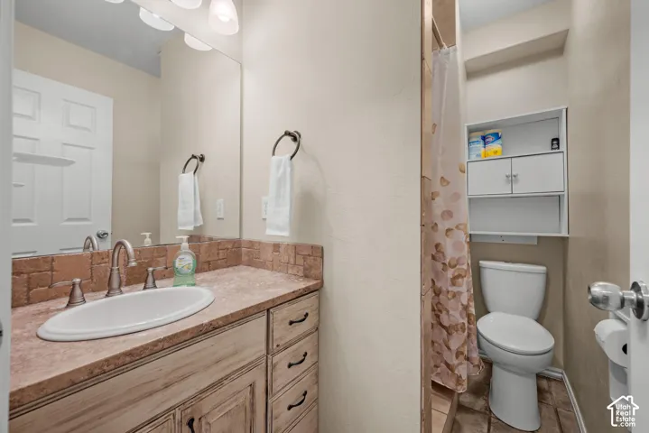 Vanity with an integrated sink, tiled countertop, wood-finish cabinetry, and a full-width mirror