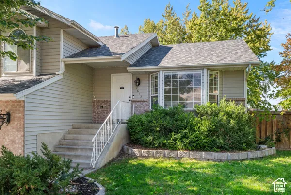 Exterior featuring horizontal siding, brick veneer accents, a multi-pane bay window, and concrete entry steps with a white metal handrail