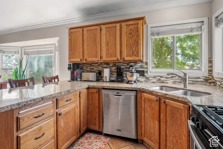 Kitchen featuring wood cabinetry, granite countertops, a mosaic tile backsplash, and stainless steel appliances