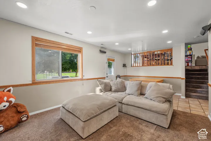 Recessed lighting illuminates this space featuring a large window with wood trim, a paneled door, and wood banister
