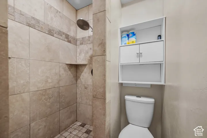 Tiled shower enclosure with a rainfall showerhead, integrated corner shelf, and a mosaic tile floor