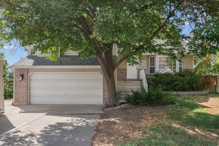 Two-car garage with brick facade, concrete driveway, front entry with steps, and bay window