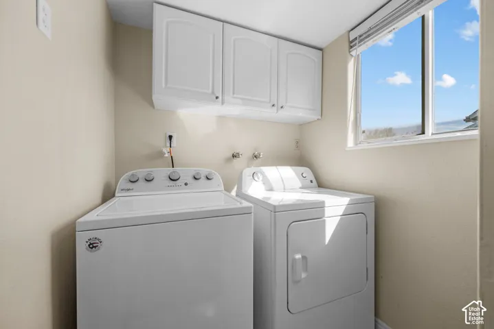 Laundry area with white upper cabinetry and a large window