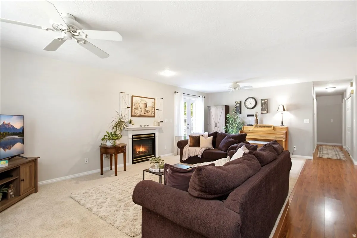 Living area featuring a fireplace with a white mantel, ceiling fans, recessed lighting, and wood-finish flooring