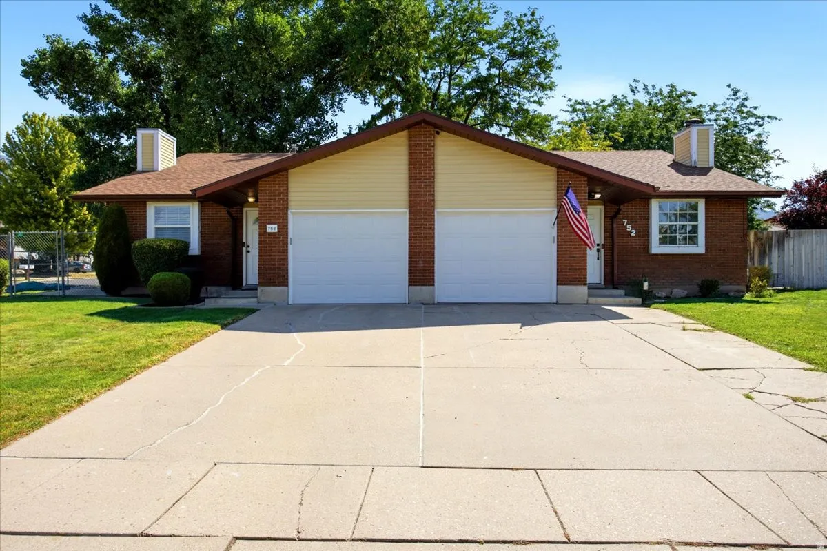 Brick exterior with cream siding, sloped roofline, and attached garage