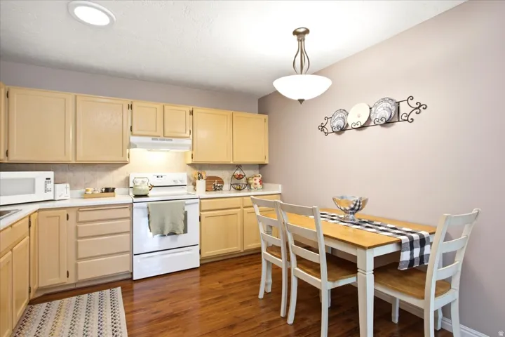 Kitchen with wood-finish flooring, recessed lighting, and a dining area featuring a pendant light fixture