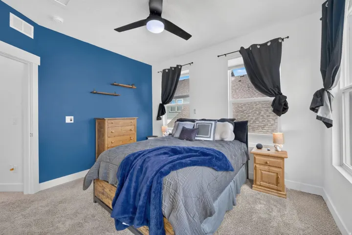 Primary bedroom with multiple windows, ceiling fan and a vibrant accent wall
