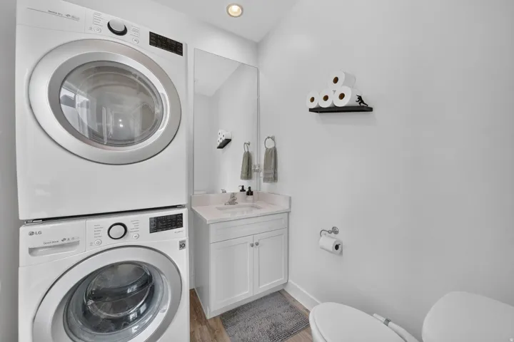Half bathroom with quartz countertops, and stackable washer and dryer