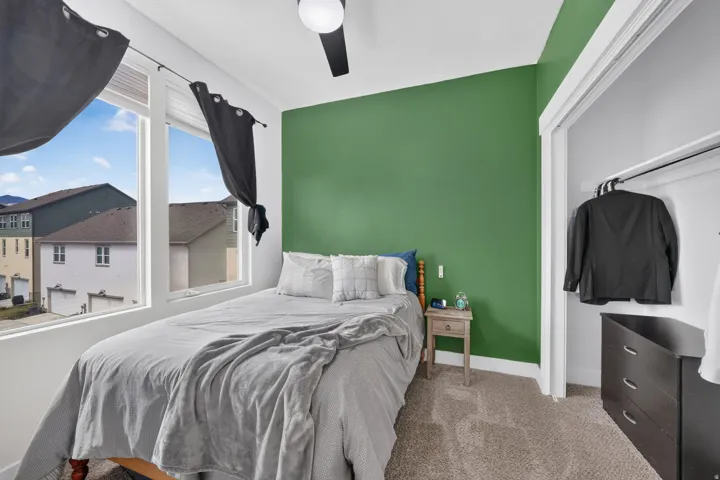 Bright interior with a bold green accent wall, natural light from large window, and ample closet space