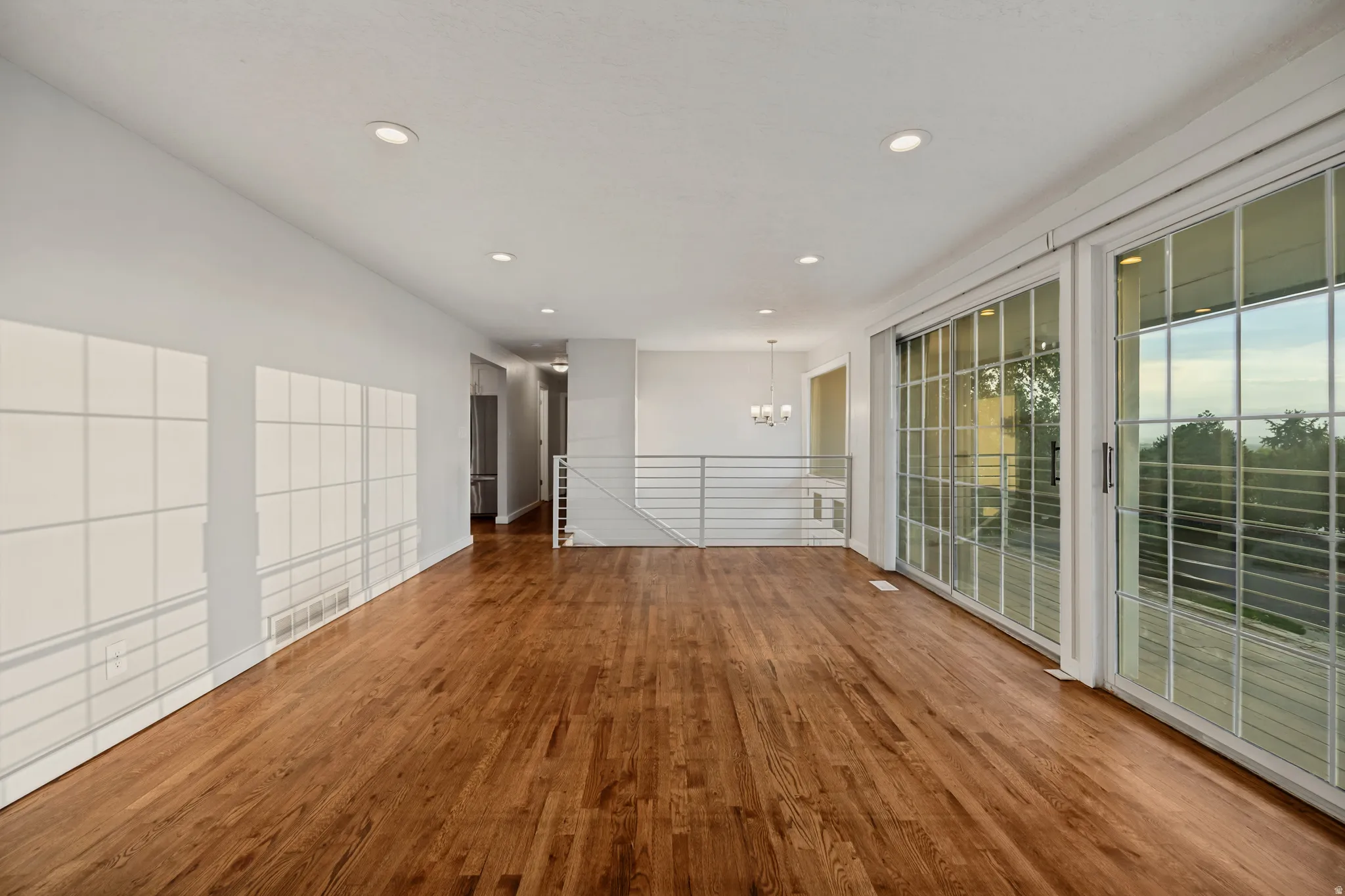 Expansive open-concept living space featuring wood-finish flooring, recessed lighting, and large sliding glass doors