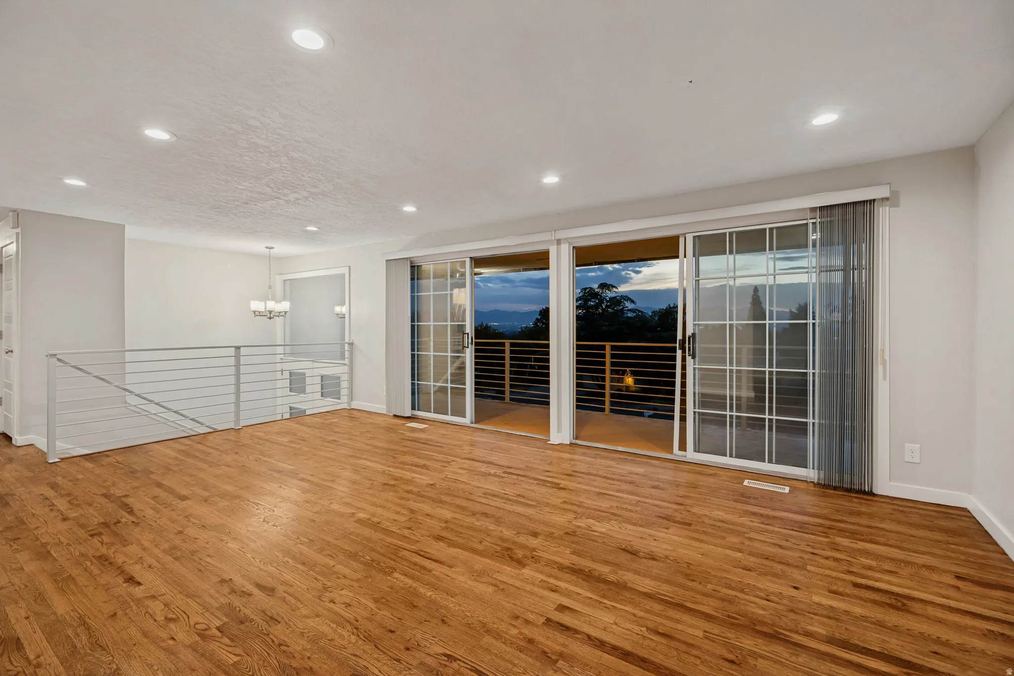 Expansive interior featuring wood-finish flooring, recessed lighting, and a cable railing system