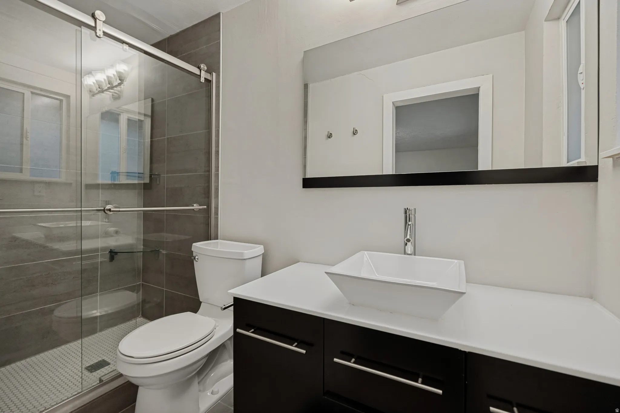 Walk-in shower with tile surround, sliding glass door, and mosaic tile floor