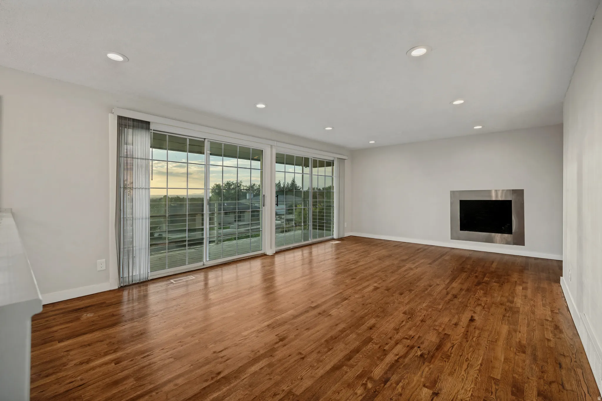 Recessed lighting, wood-finish flooring, sliding glass doors, built-in fireplace, and white walls