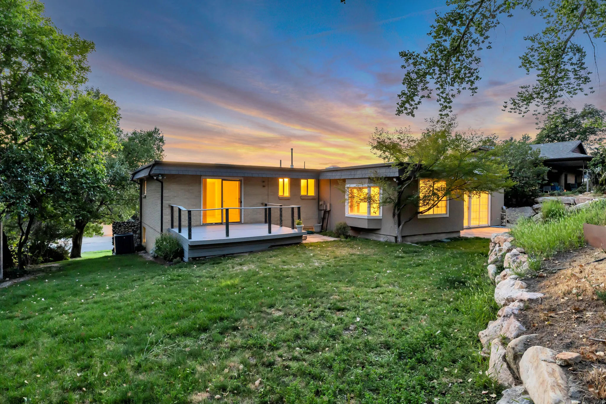 Expansive lawn with mature trees and a rock retaining wall