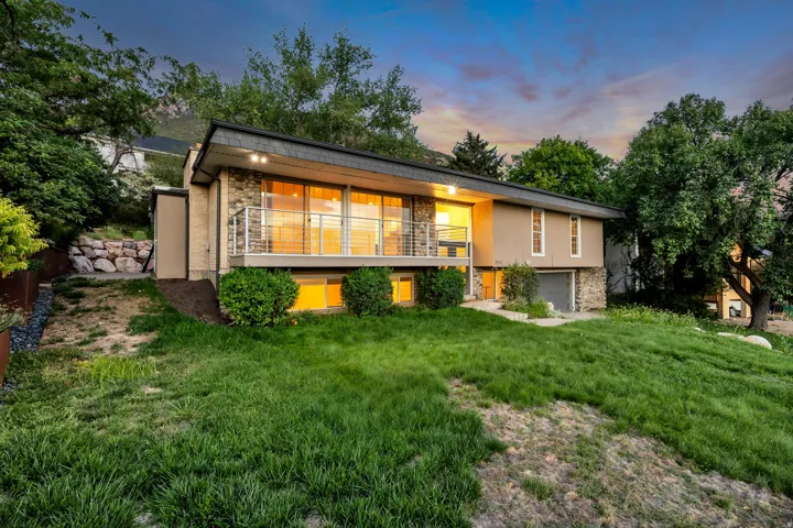 Contemporary exterior with stone facade, expansive windows, front balcony with cable railing, and integrated garage