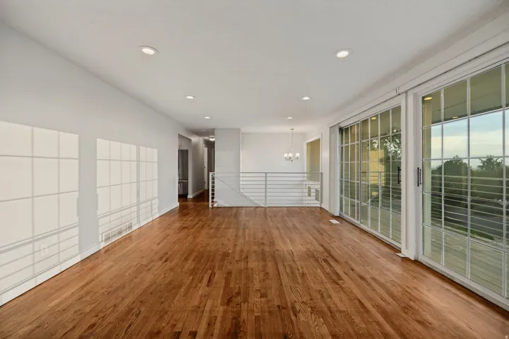 Expansive open-concept living space featuring wood-finish flooring, recessed lighting, and large sliding glass doors