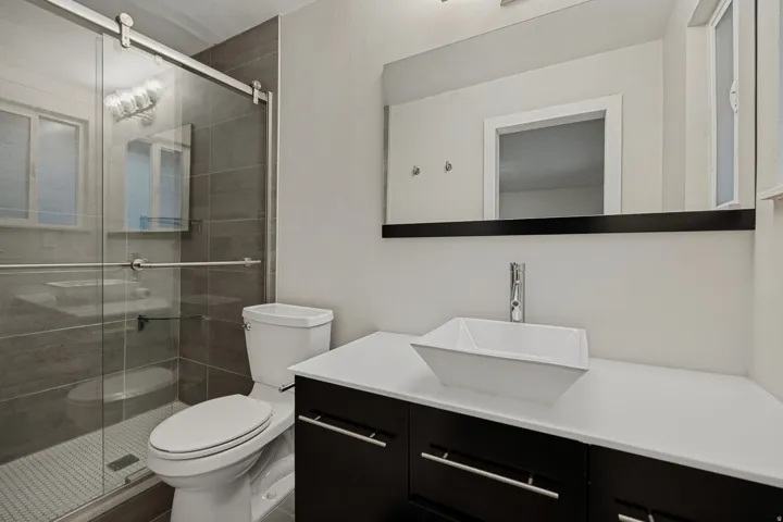 Walk-in shower with tile surround, sliding glass door, and mosaic tile floor