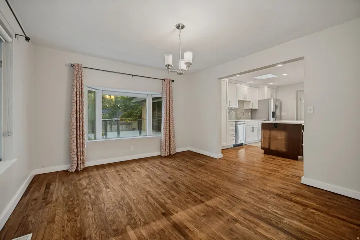 Hardwood flooring, bay window, recessed lighting, white cabinetry, and a kitchen island