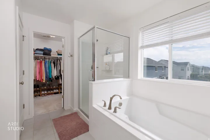 Spacious bathroom featuring a glass-enclosed shower, built-in soaking tub with brushed nickel fixtures, and a large window