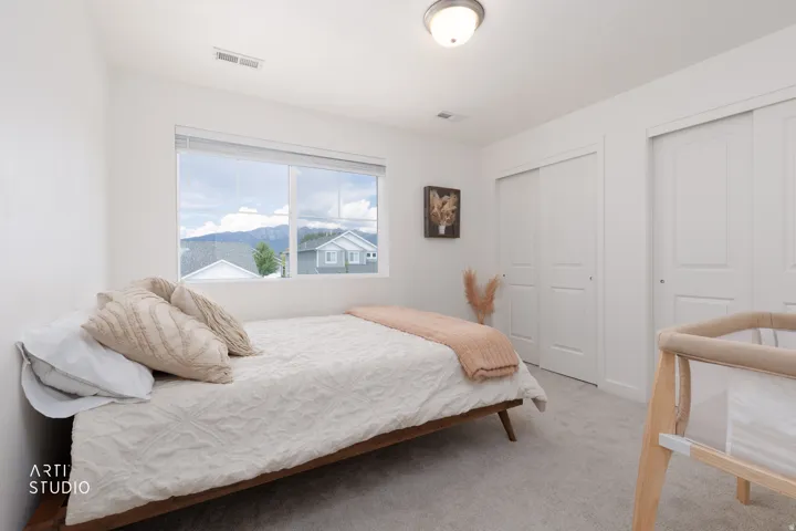 Carpeted room with a flush-mount ceiling light, a large window, and two bi-fold closet doors
