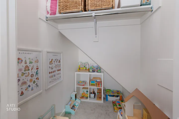 Dedicated under-stair storage space featuring built-in shelving with adjustable compartments, white painted walls, and neutral flooring